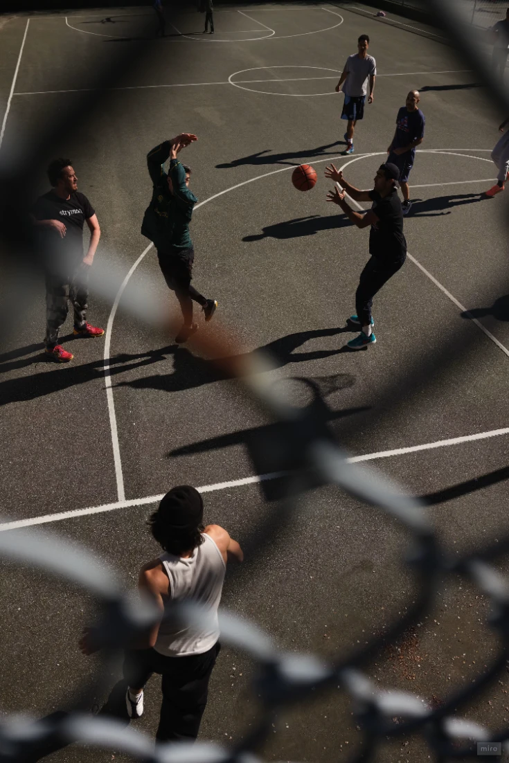 Basketball players passing the ball on a sunlit outdoor court